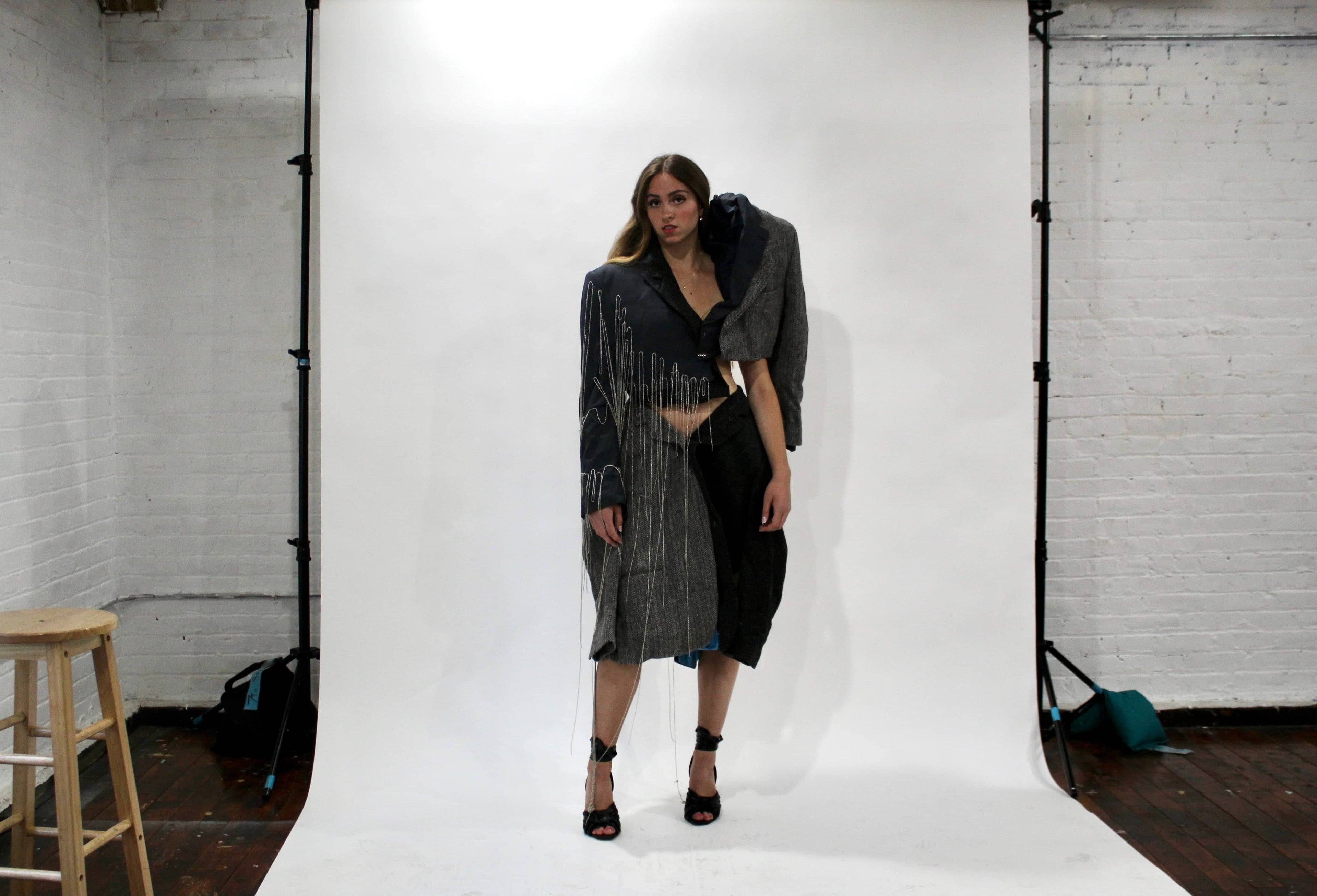 Model wearing sculptural blazer skirt and matching blazer top with silver hand-beaded chains from the Corii Burns MHII Collection during New York Fashion Week fitting.