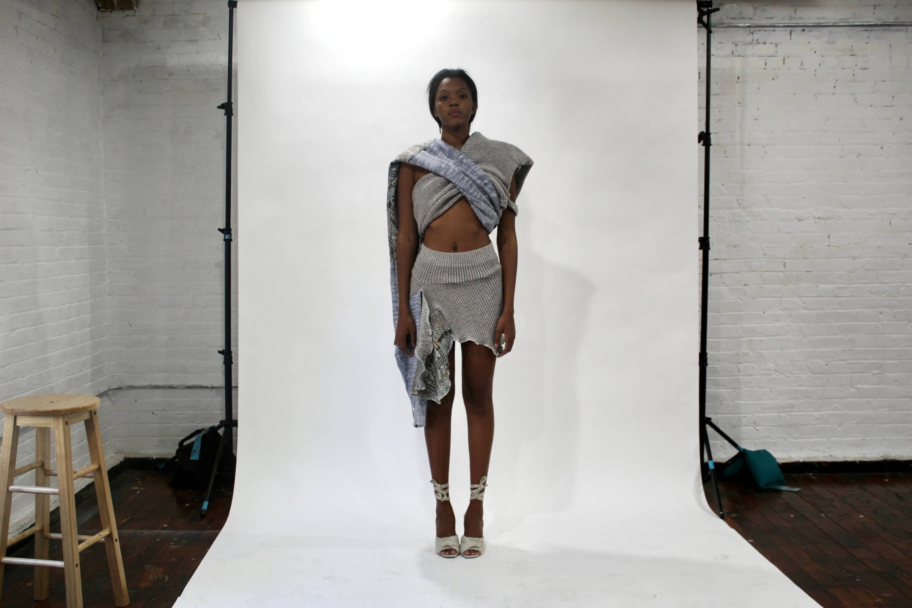 Model wearing one-size-fits-all deconstructed scarf shirt and matching knit skirt from the Corii Burns MHII Collection during NYC studio fitting for New York Fashion Week.