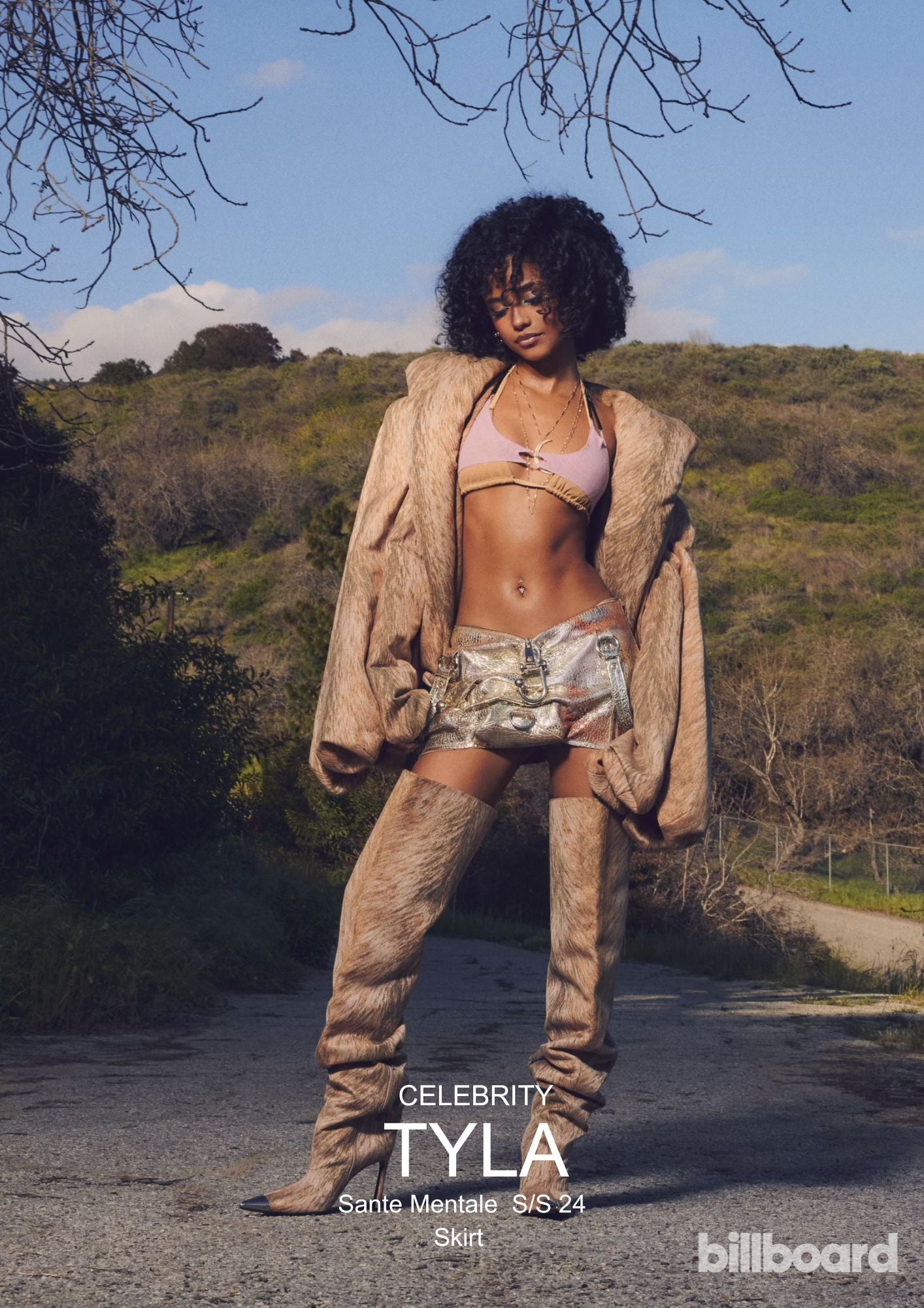 South African singer and songwriter Tyla Laura Seethal wearing the Corii Burns Sante Mentale SS24 Skirt for Billboard Magazine while standing on concrete back country road while wearing large beige overcoat and high heeled boots; A striking woman in a chic bikini top and fashionable boots stands poised on a rustic dirt road, radiating bold elegance.